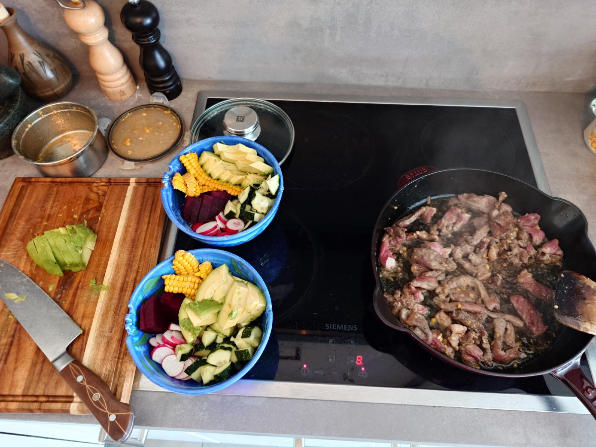 Avocado sliced, beef searing in cast iron