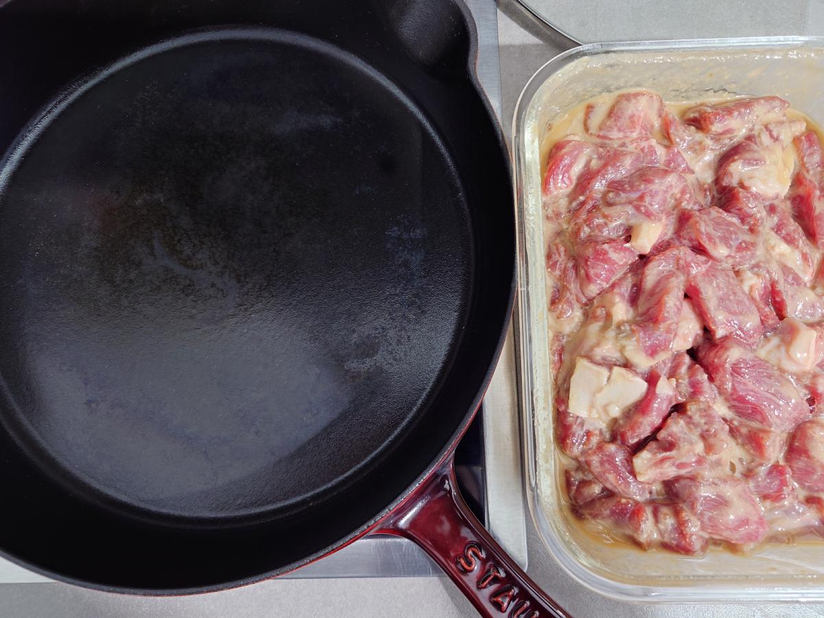 Marinated beef next to the cold cast iron pan