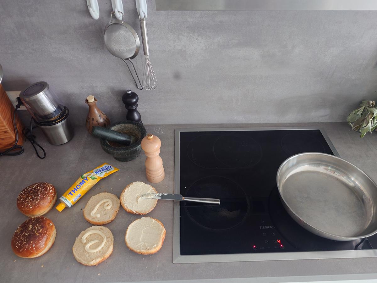 Buns spread with mayonnaise, the pan heating alongside