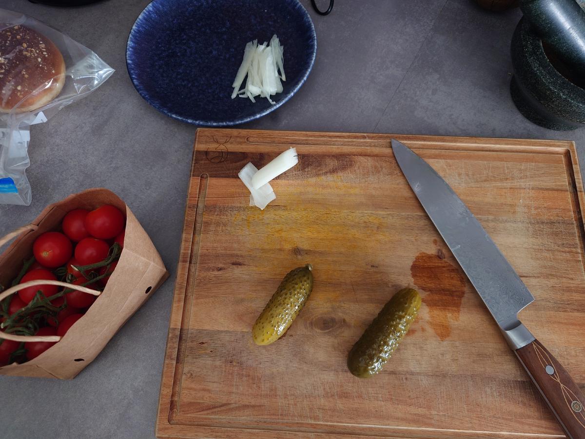 Pickles, tomatoes and onion prepped on the board
