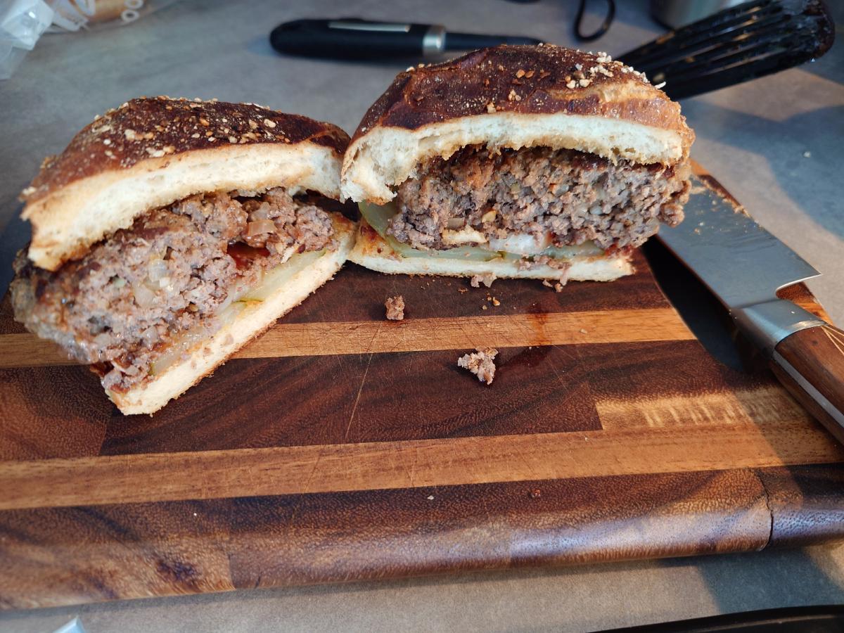 A finished burger cut in half, the patty cooked through and juicy