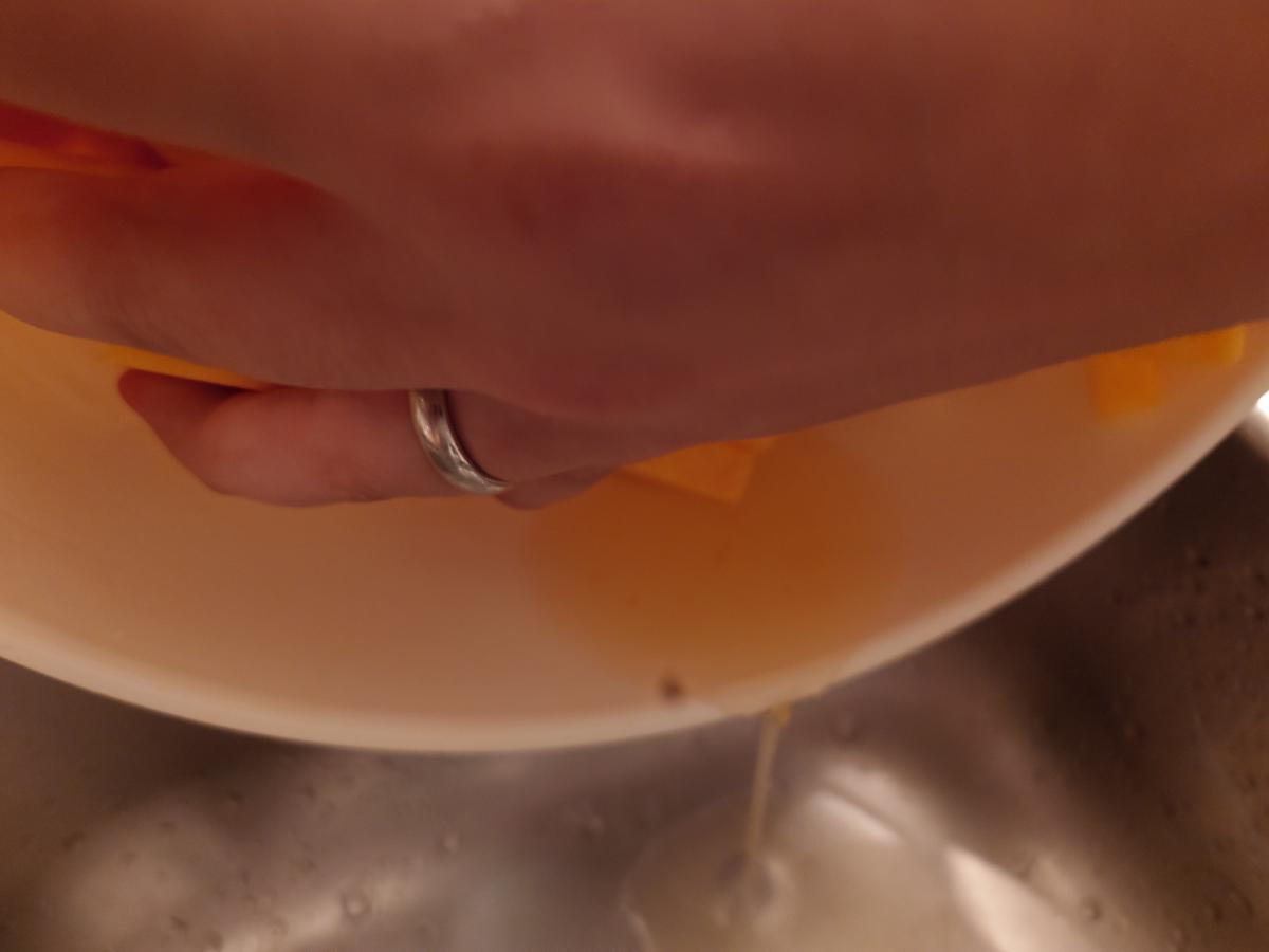 The bowl tipped over the sink, orange liquid running out
