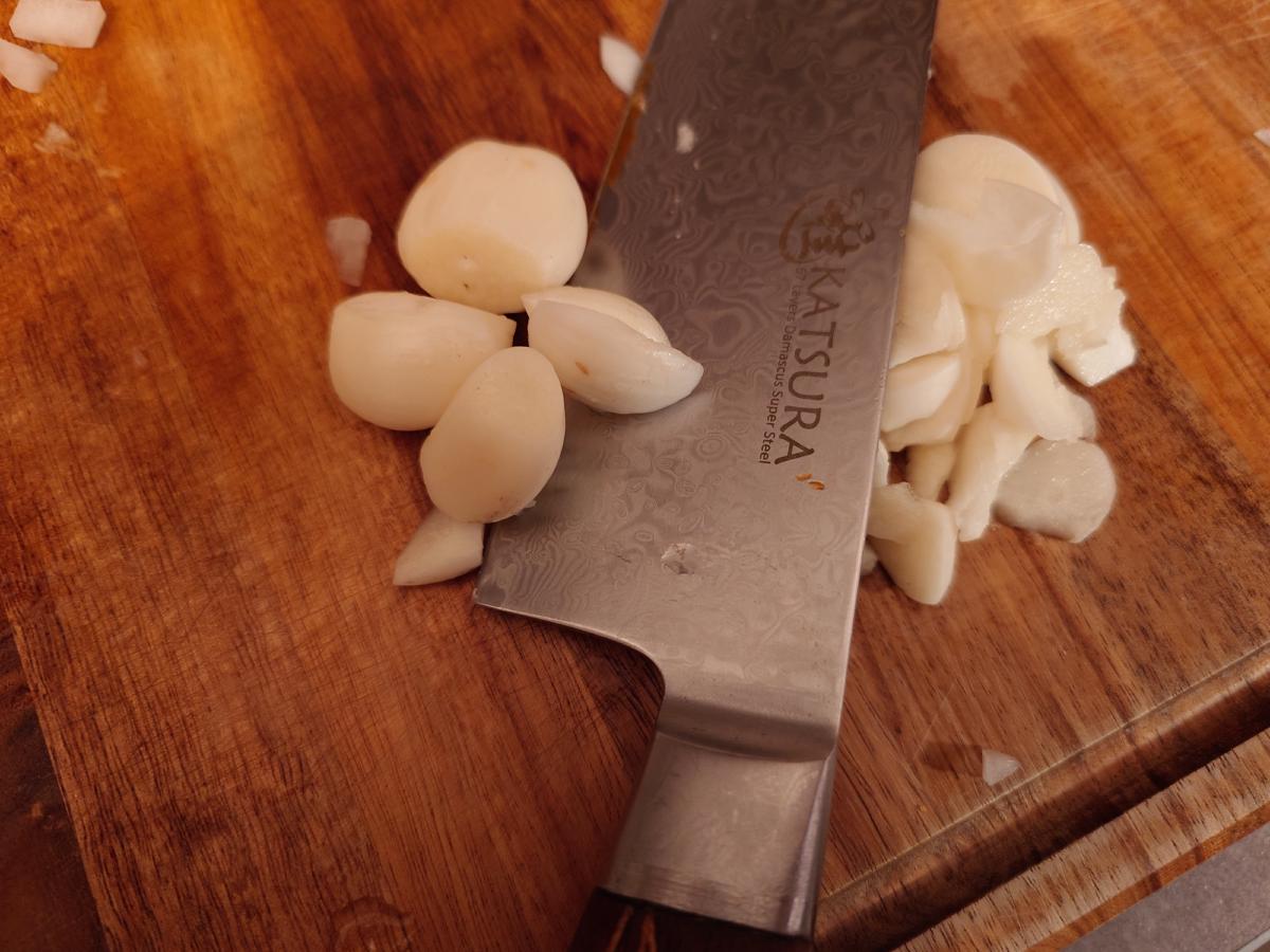 Peeled garlic cloves and a chopped pile on the board