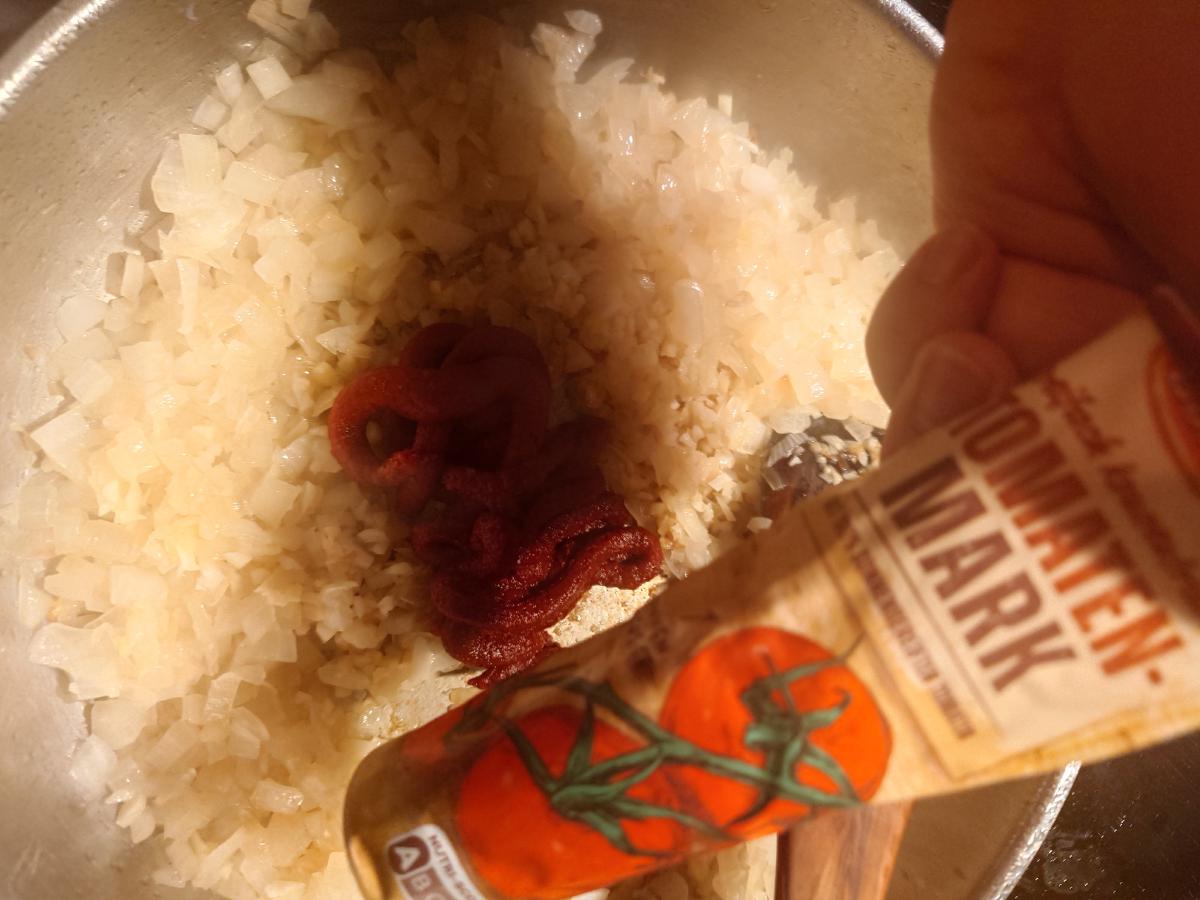 Tomato paste squeezed from the tube into the onion