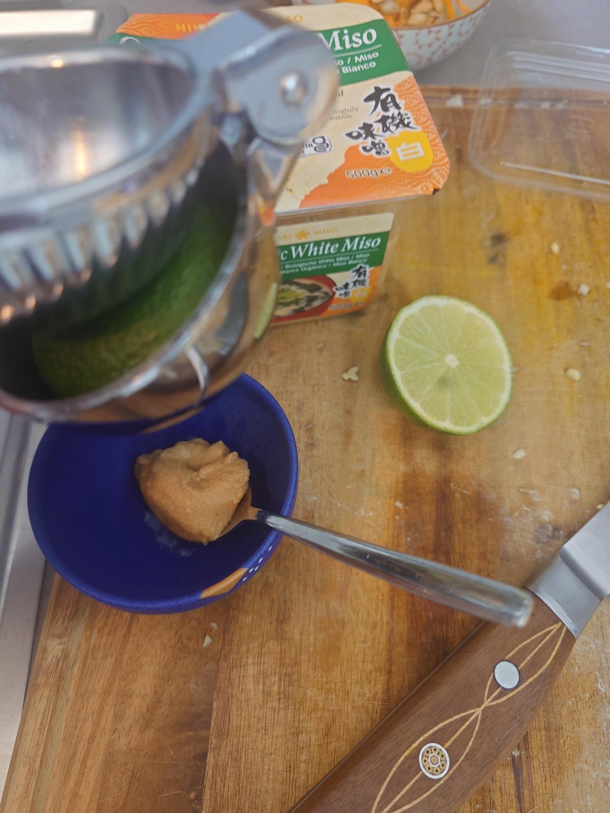 A lime half in the juicer, white miso in a small blue bowl