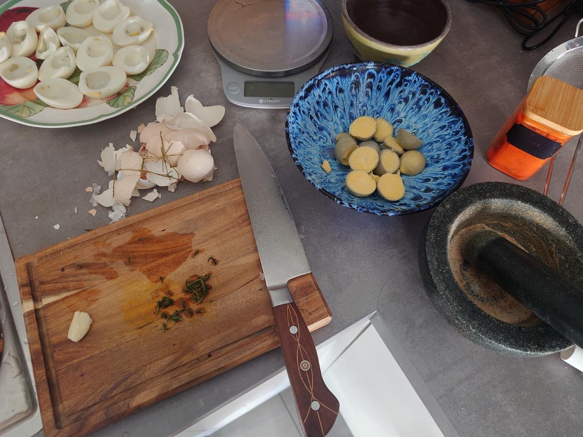 Yolks in the bowl, herbs and garlic chopped on the board