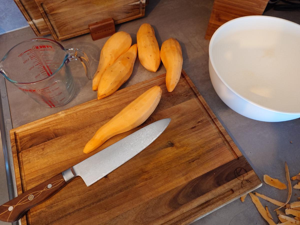Sweet potatoes peeled, one going under the knife