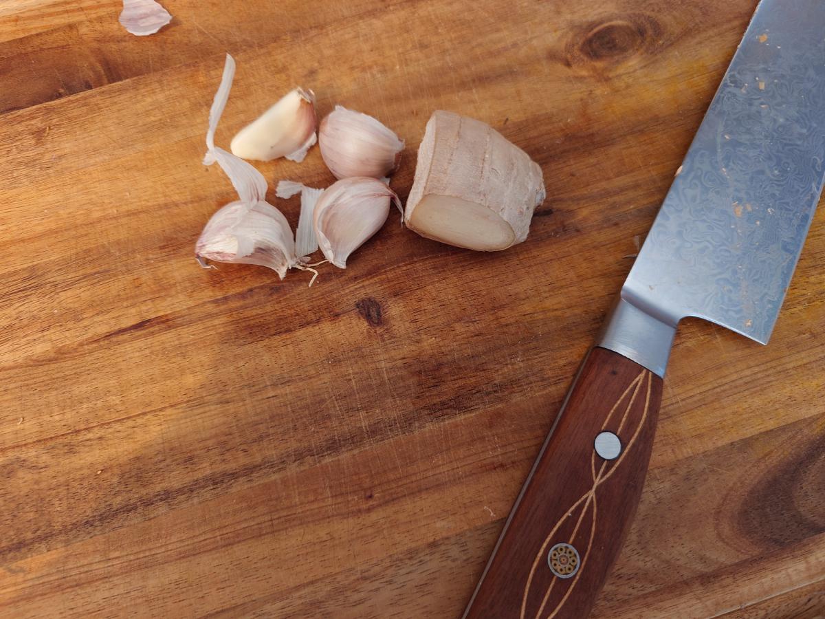 Garlic cloves and a knob of ginger on the board