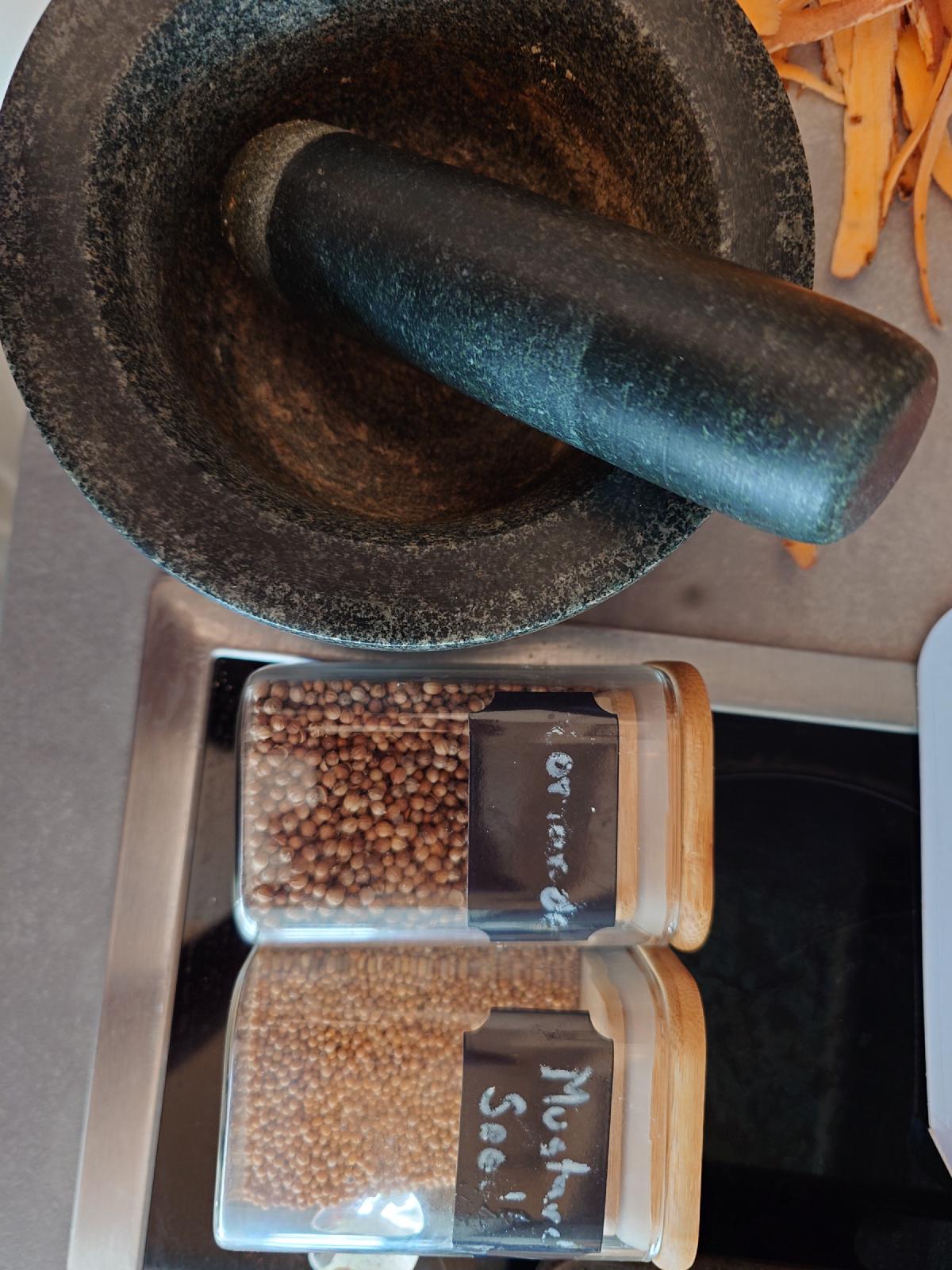Coriander and mustard seed next to the mortar