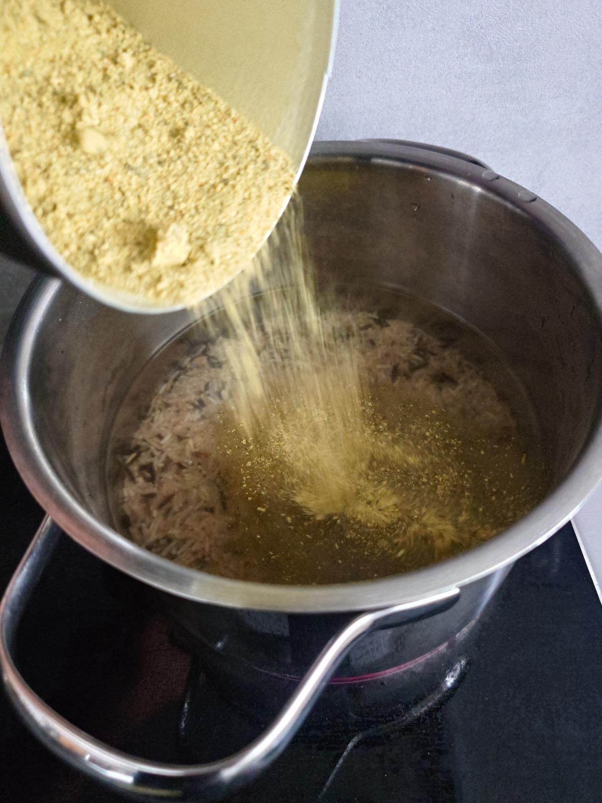 Stock powder poured over rice in the pot