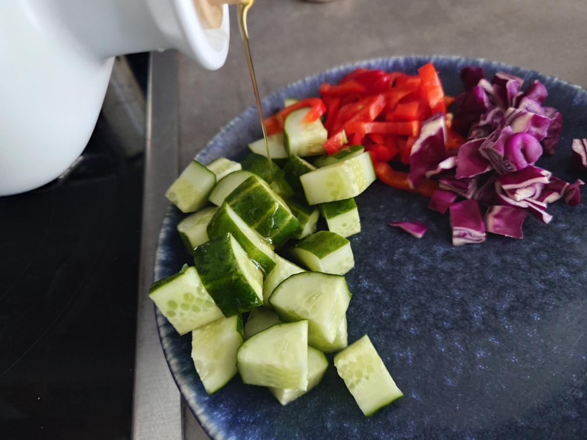 Cucumber, pepper and cabbage on the plate with oil poured over