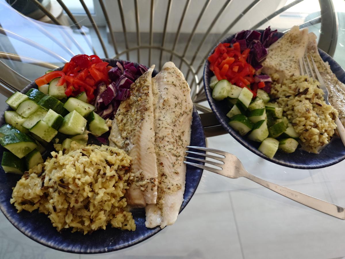 Two plates: fish, seasoned rice, cucumber, pepper and red cabbage
