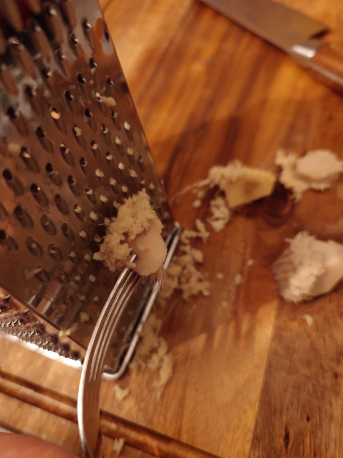 Ginger grated down a box grater, held against the blade with a fork