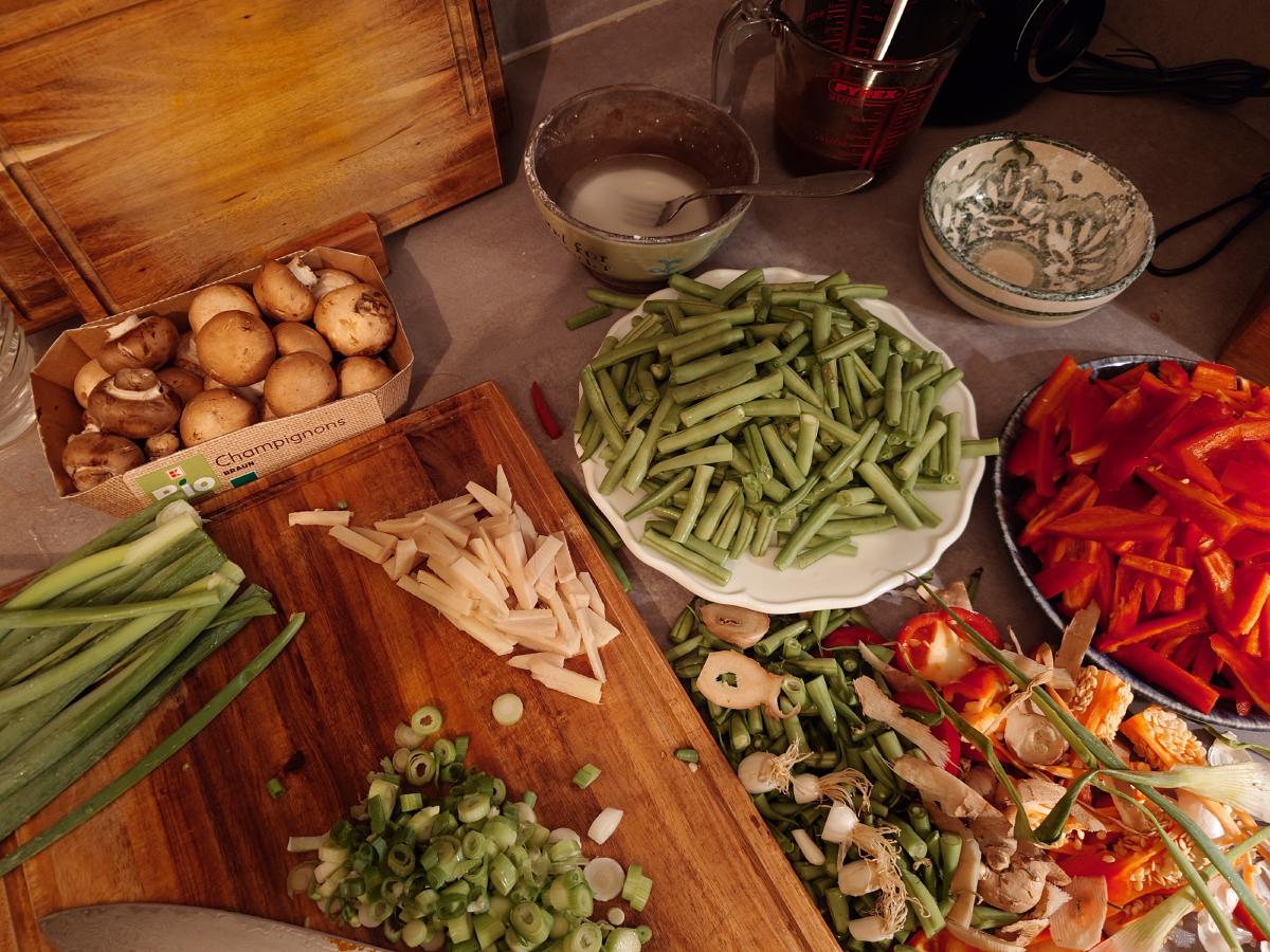 Brown mushrooms in their box, scallions sliced into rings, ginger matchsticks, beans, pepper strips, the slurry bowl and the sauce jug