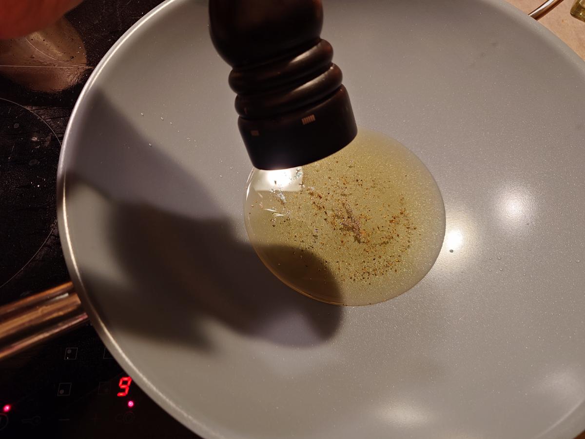 A wooden mill grinding pepper into the pool of oil