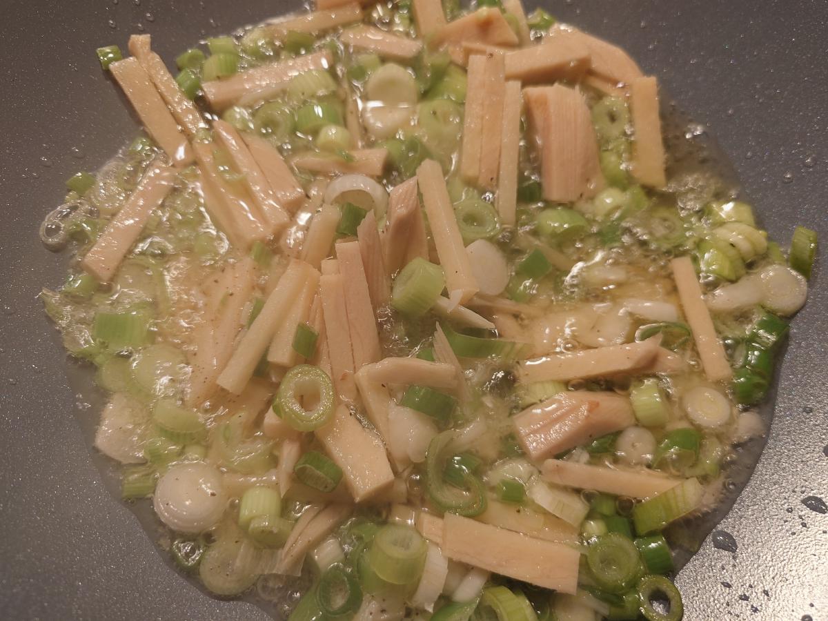 Ginger matchsticks and sliced scallions bubbling in the oil