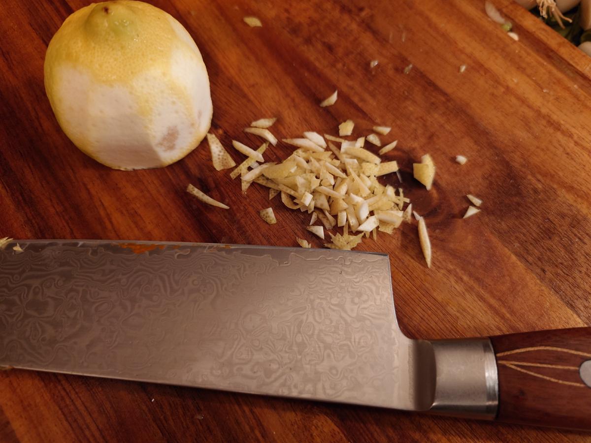 A pared lemon on the board beside chopped zest