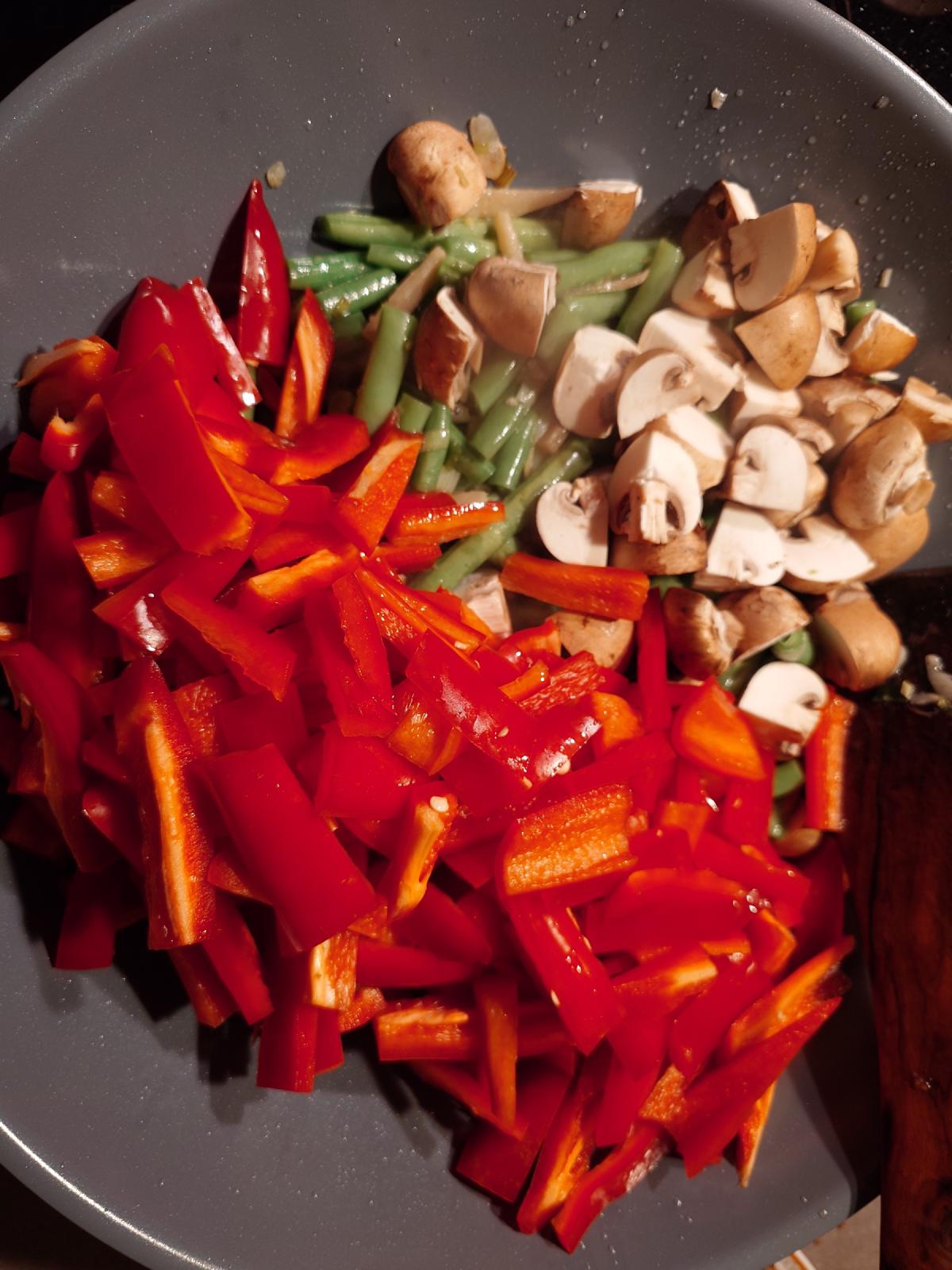 Pepper strips and quartered mushrooms added, a dried red chili among them