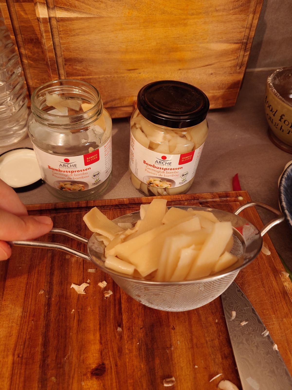 One jar of bamboo shoots emptied into a sieve, a second still full behind it