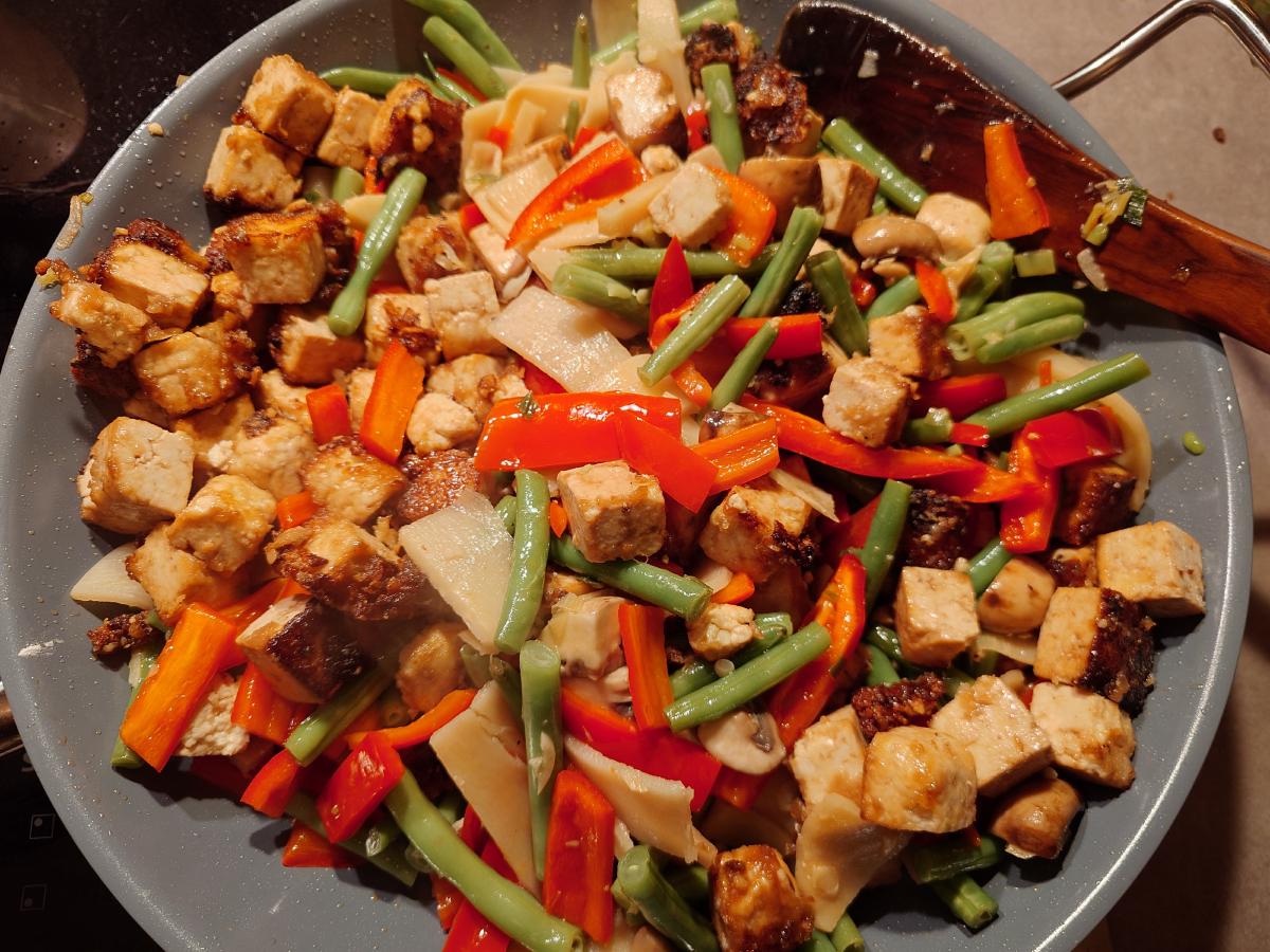 The fried tofu tipped back into the wok