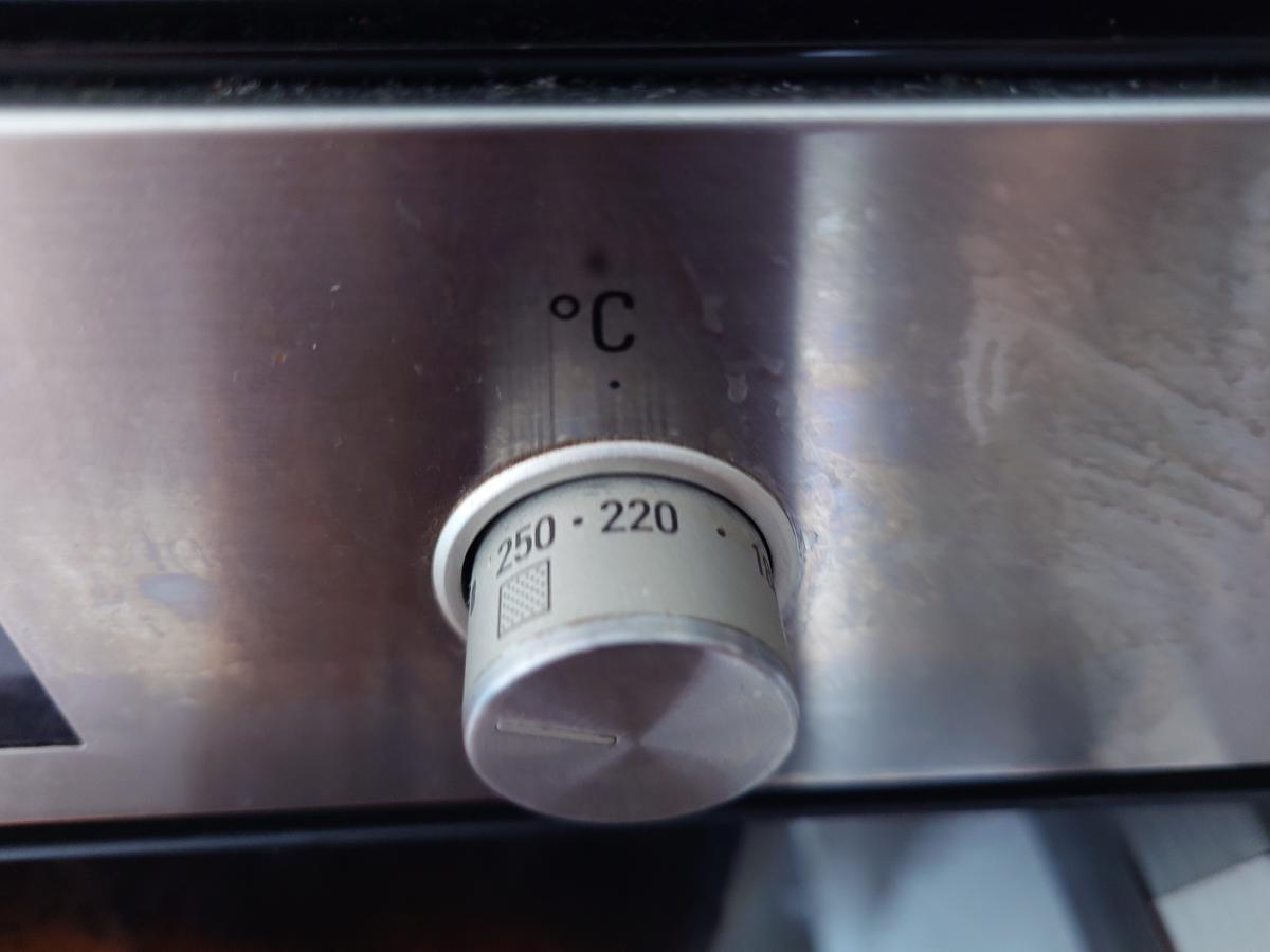 The oven thermostat knob turned between 220 and 250