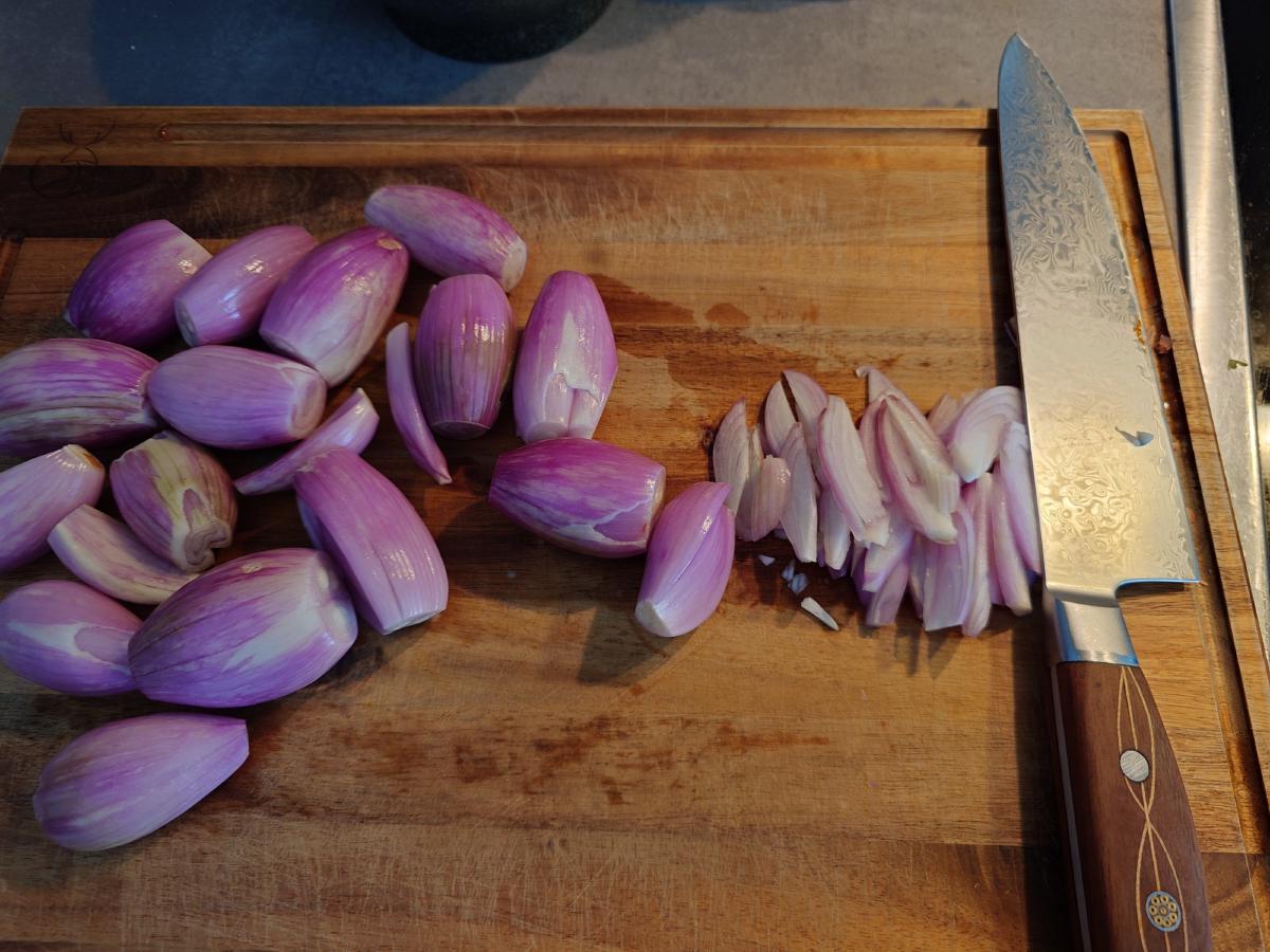 The first shallots cut into thick lengthwise pieces beside the whole ones