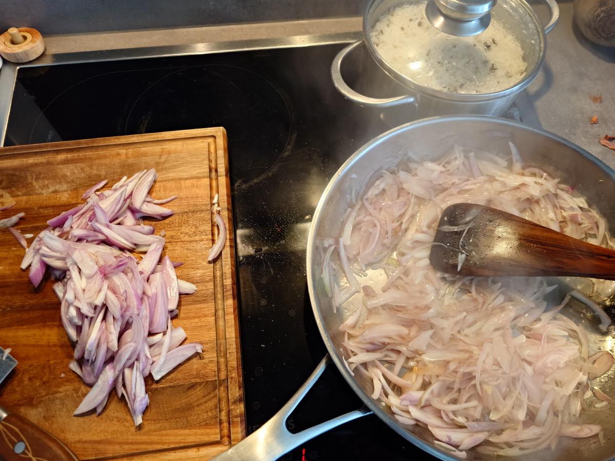 The pan full of shallots going translucent, the rice pot steaming behind