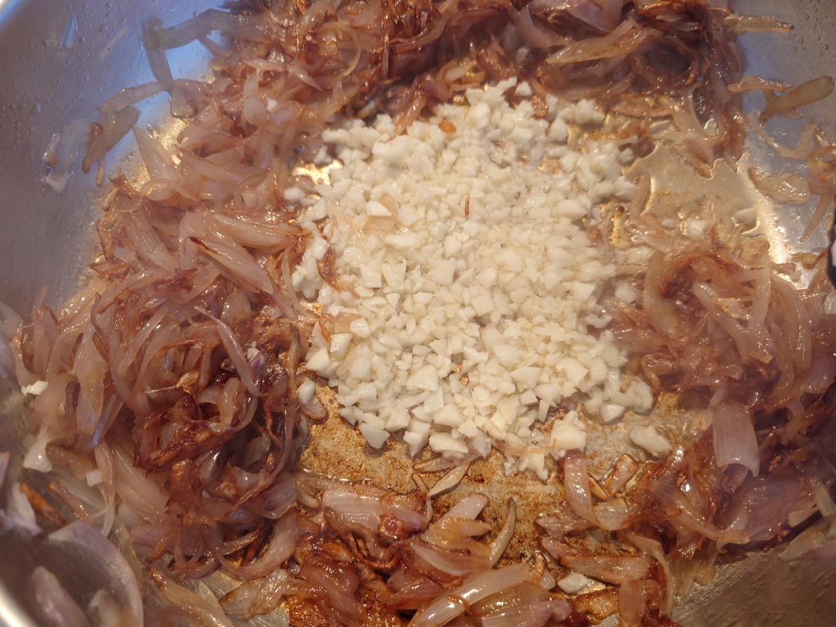 The garlic tipped into a cleared well in the middle of the shallots