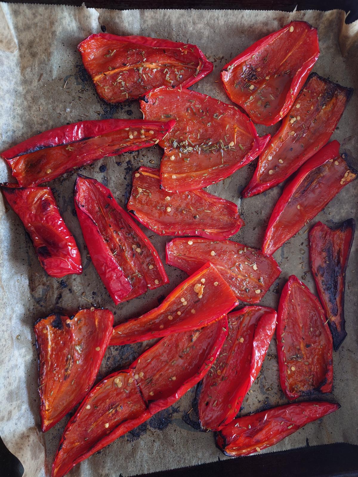 The same strips roasted, edges blackened, rosemary needles across them