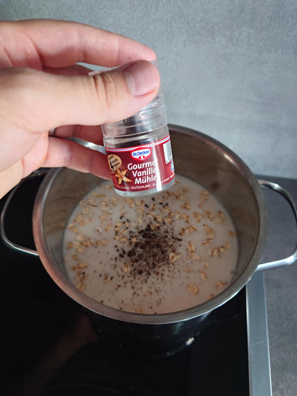 A vanilla grinder held over the pot, dark specks scattered across the surface