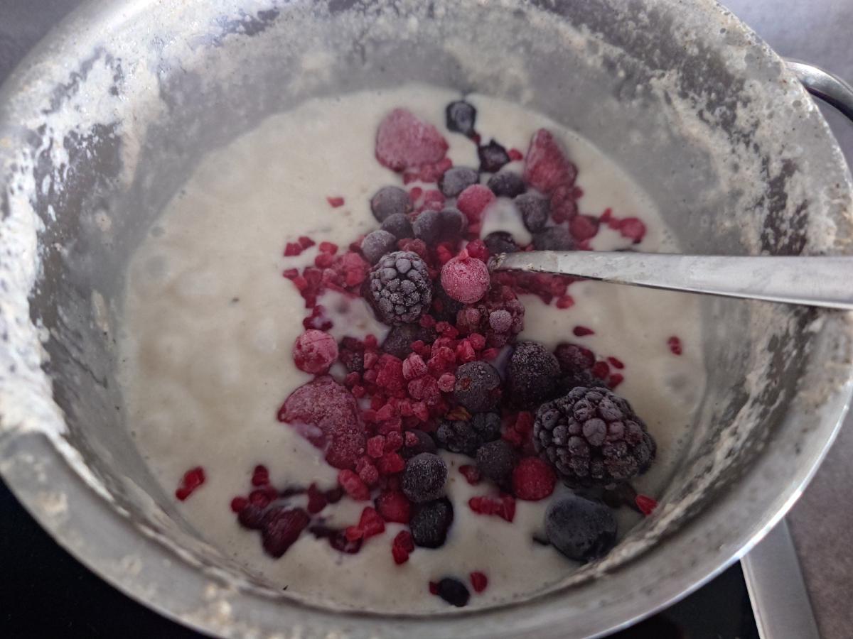 Frozen berries sitting on the hot oats, still frosted, spoon alongside