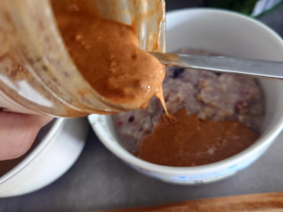 Peanut butter scooped from its tub onto a bowl of oatmeal