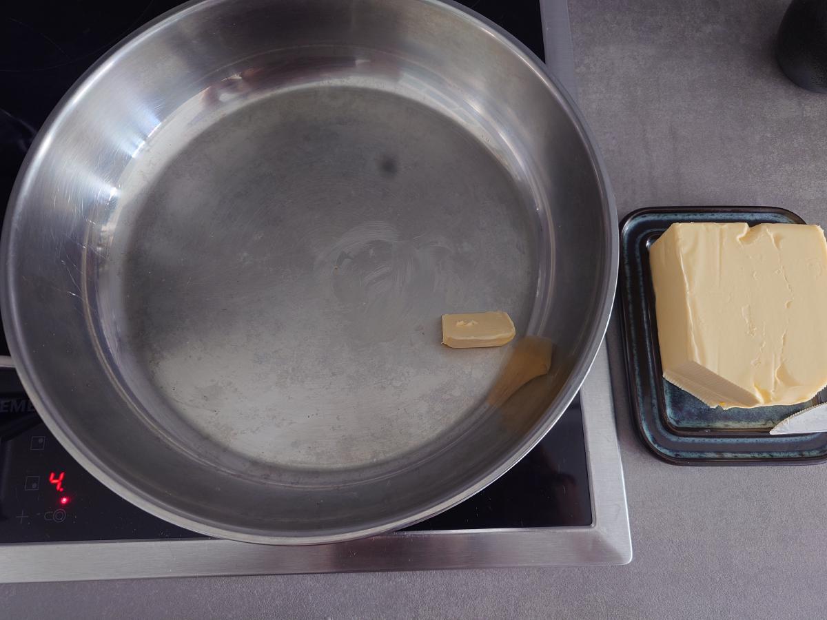 Steel pan on the induction hob at 4.5 with a piece of butter melting, the butter block on the counter below