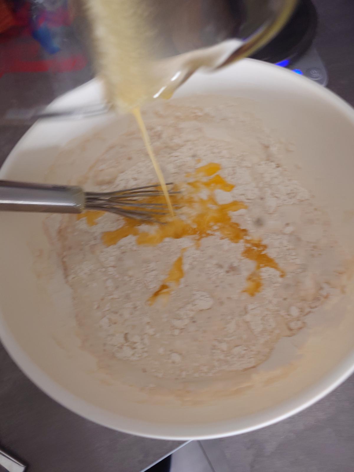 Melted butter poured in from the jug, bright yellow across the flour