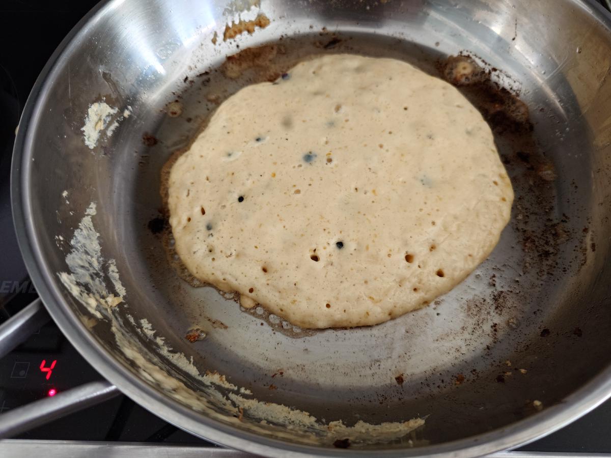 Third pancake set at the edges, bubbles open in the middle