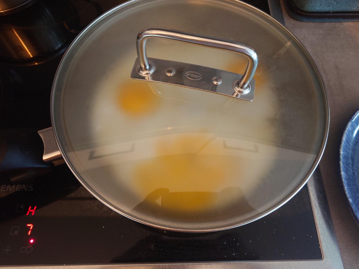 Glass lid on the pan, steam clouding the underside