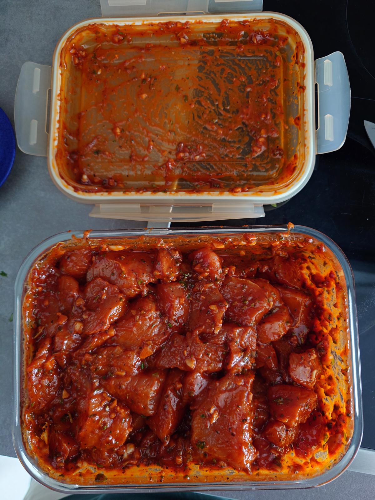 Two containers of turkey coated in the red marinade