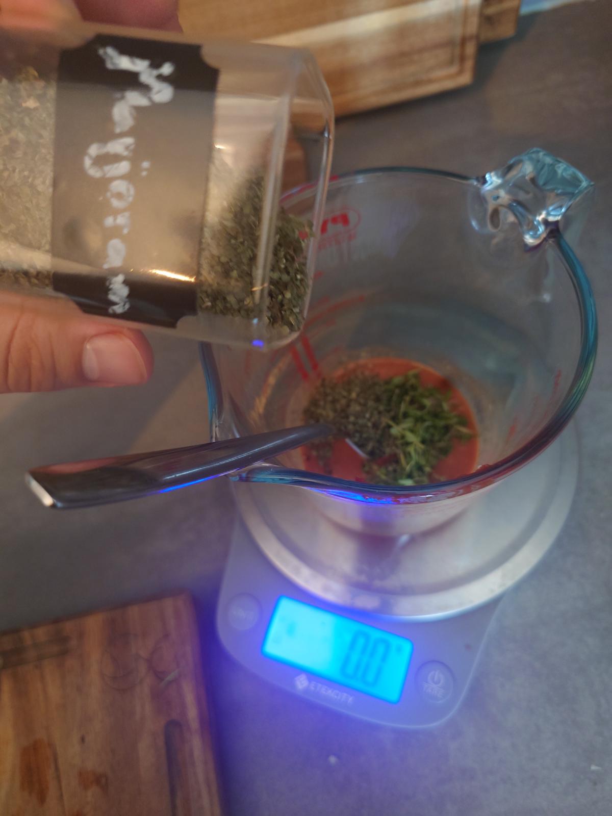 Dried marjoram spooned into the cup