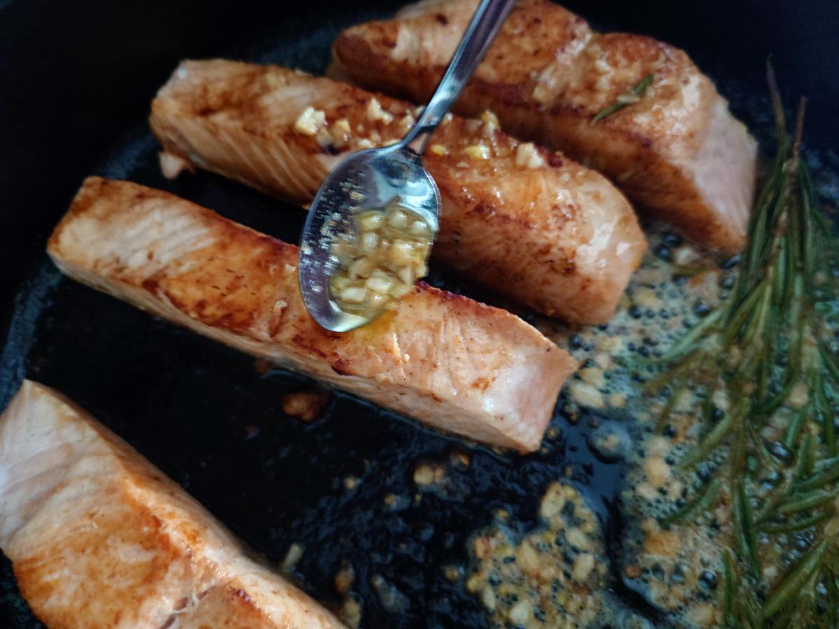 Spooning the garlic butter over the salmon