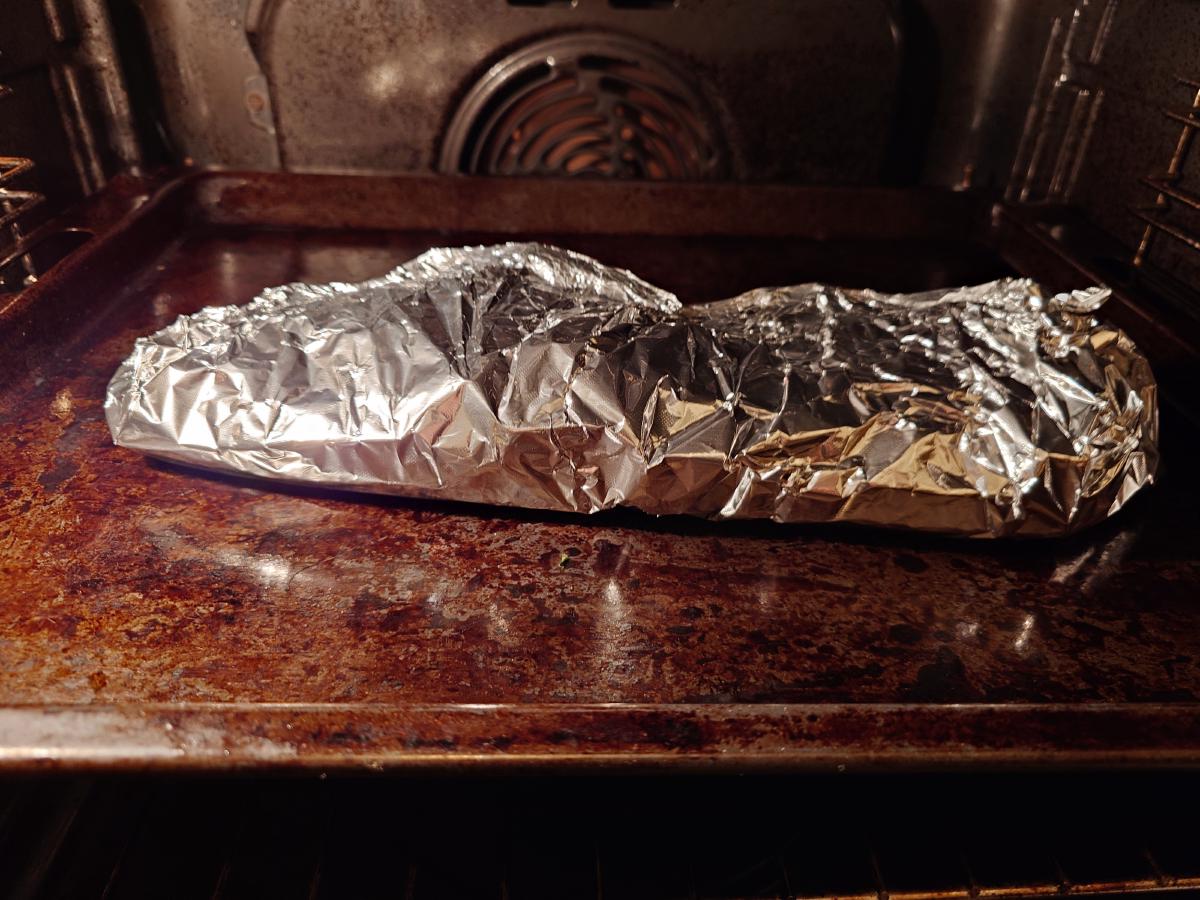 The sealed foil parcel on a tray in the oven