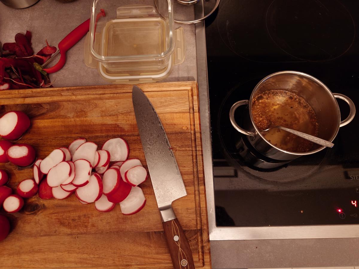 Radishes being sliced while the brine cools on the hob