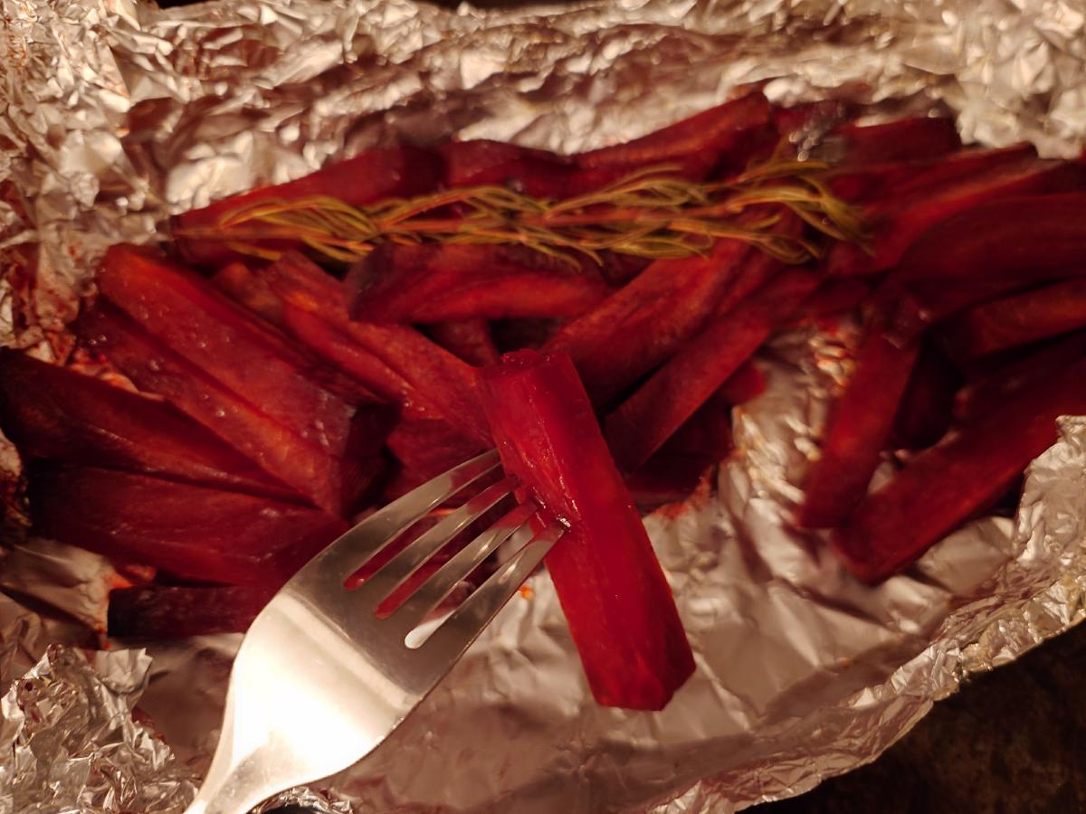 The foil opened, a fork going into a beet baton