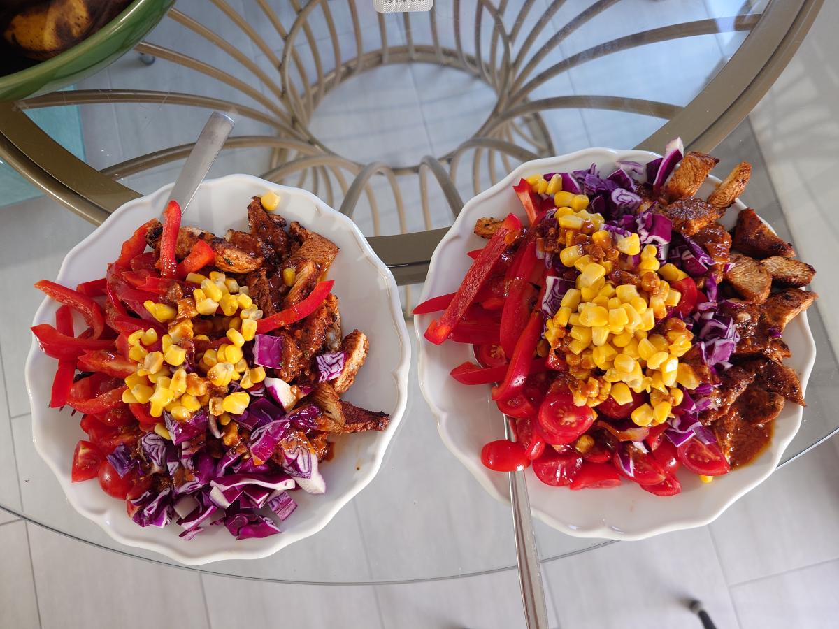 Two plates of sliced turkey with red pepper, corn, red cabbage and tomato