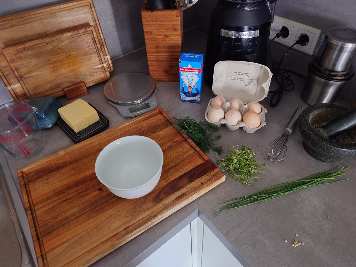 Eggs, butter, salt, herbs and the scale set out on the counter