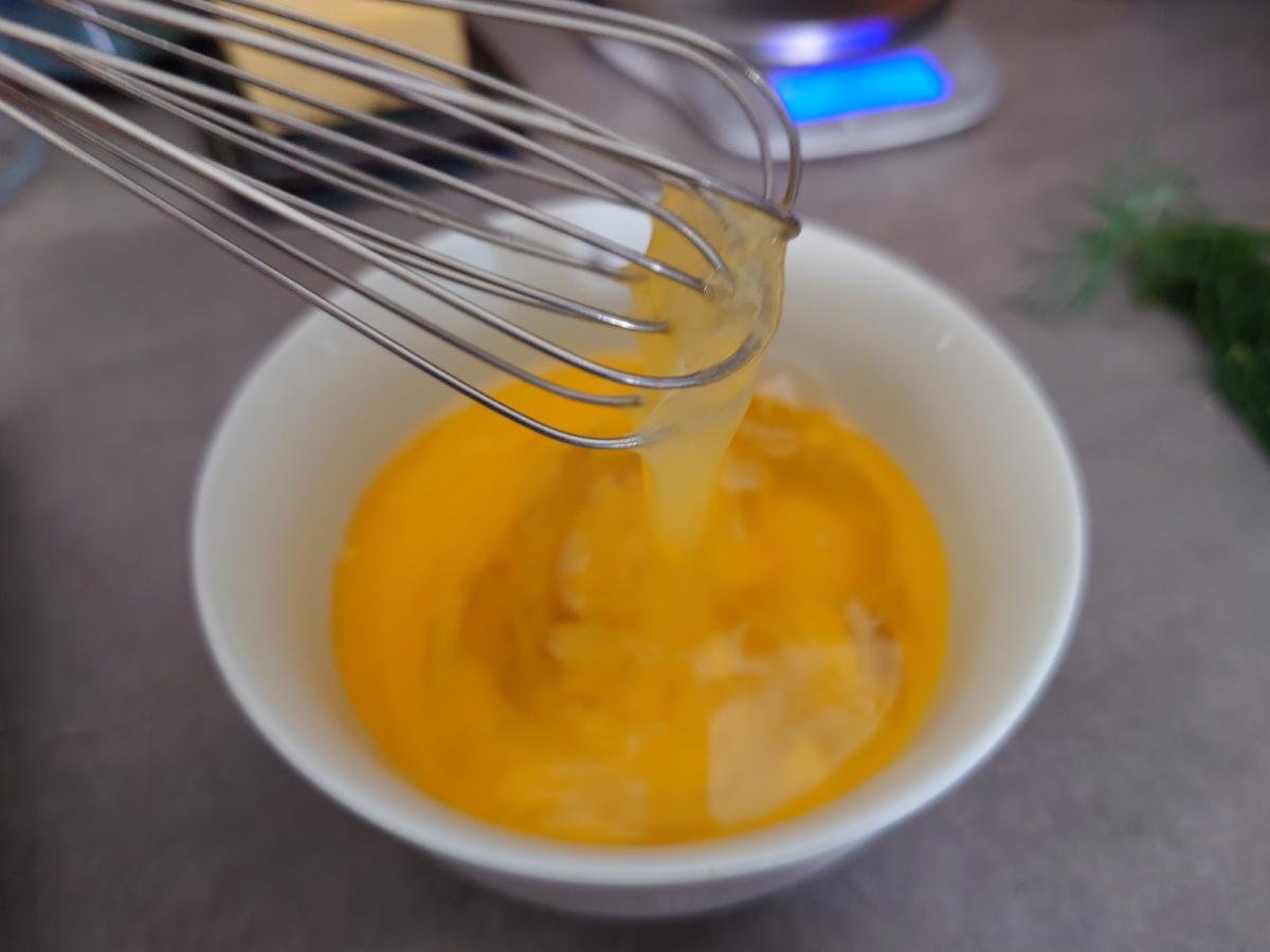 Whisk lifting out of the cracked eggs