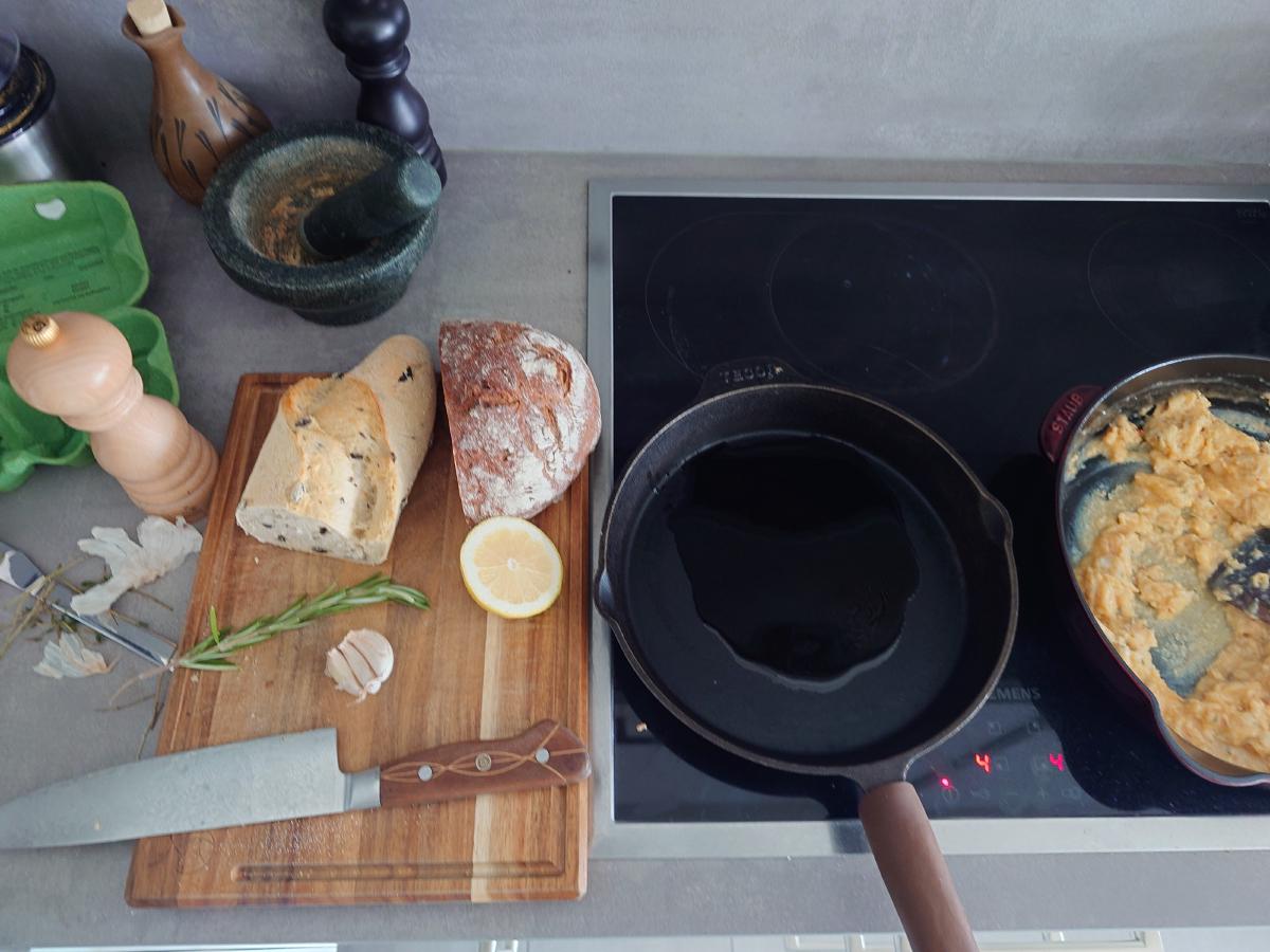 Oiled pan with rosemary, garlic and lemon on the board