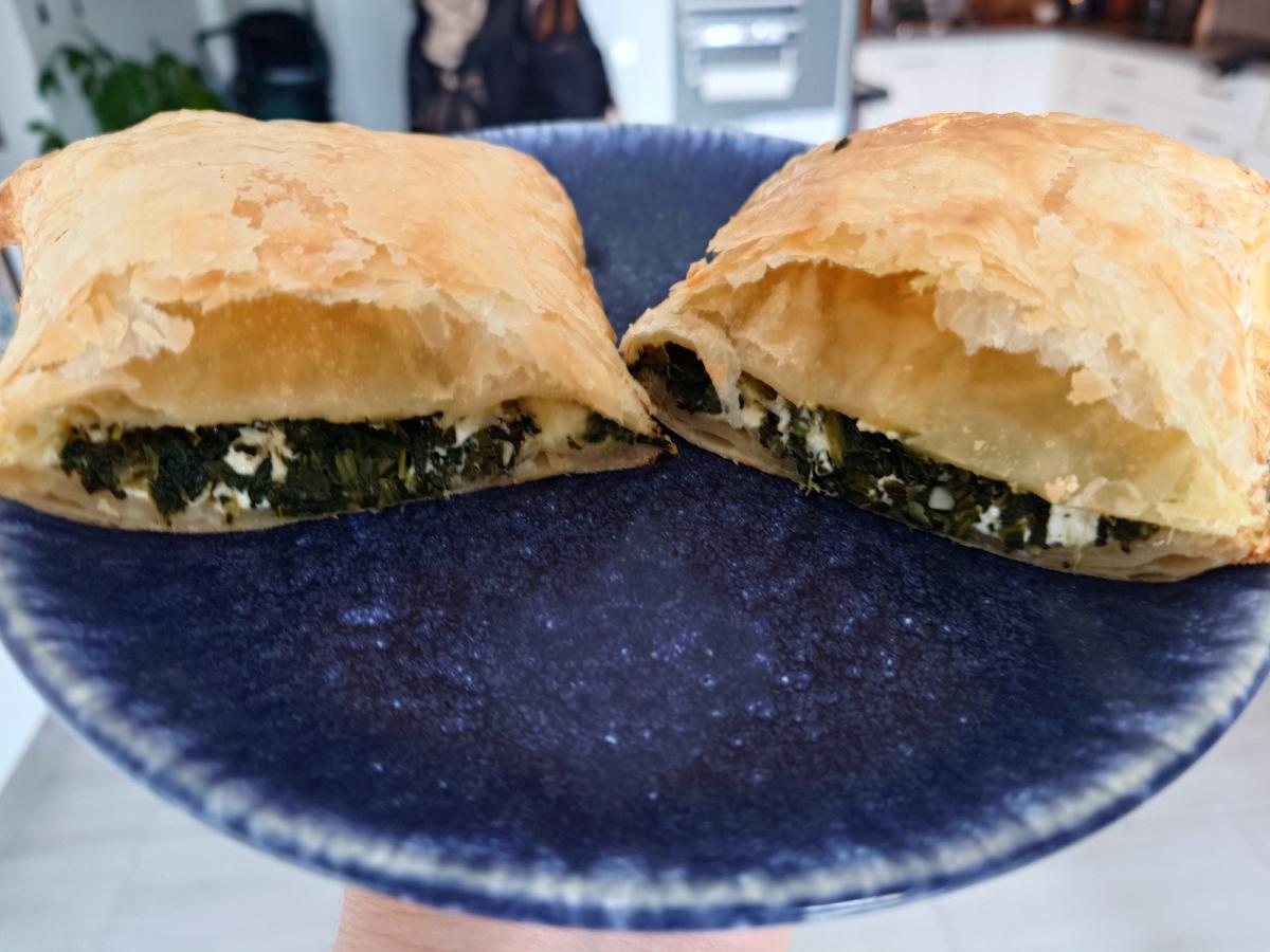 A parcel cut in half, showing the spinach and feta filling and the air gap under the top