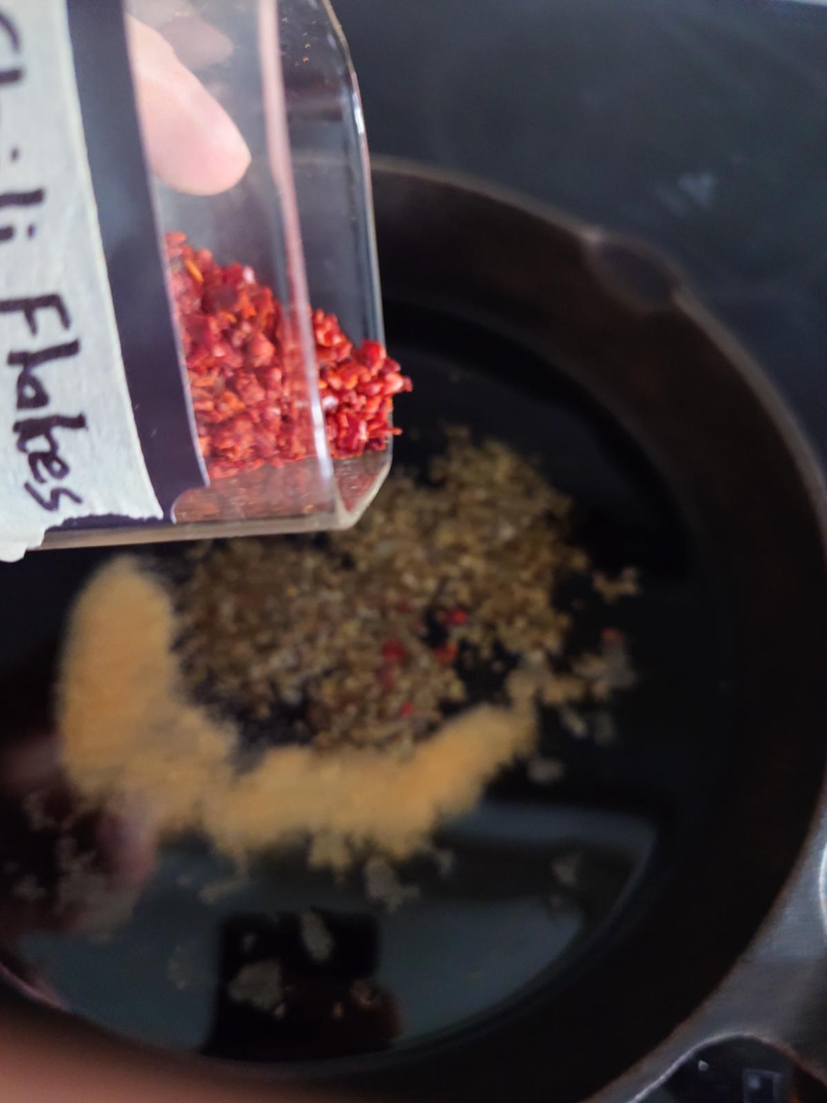 Chili flakes going in from a labelled shaker