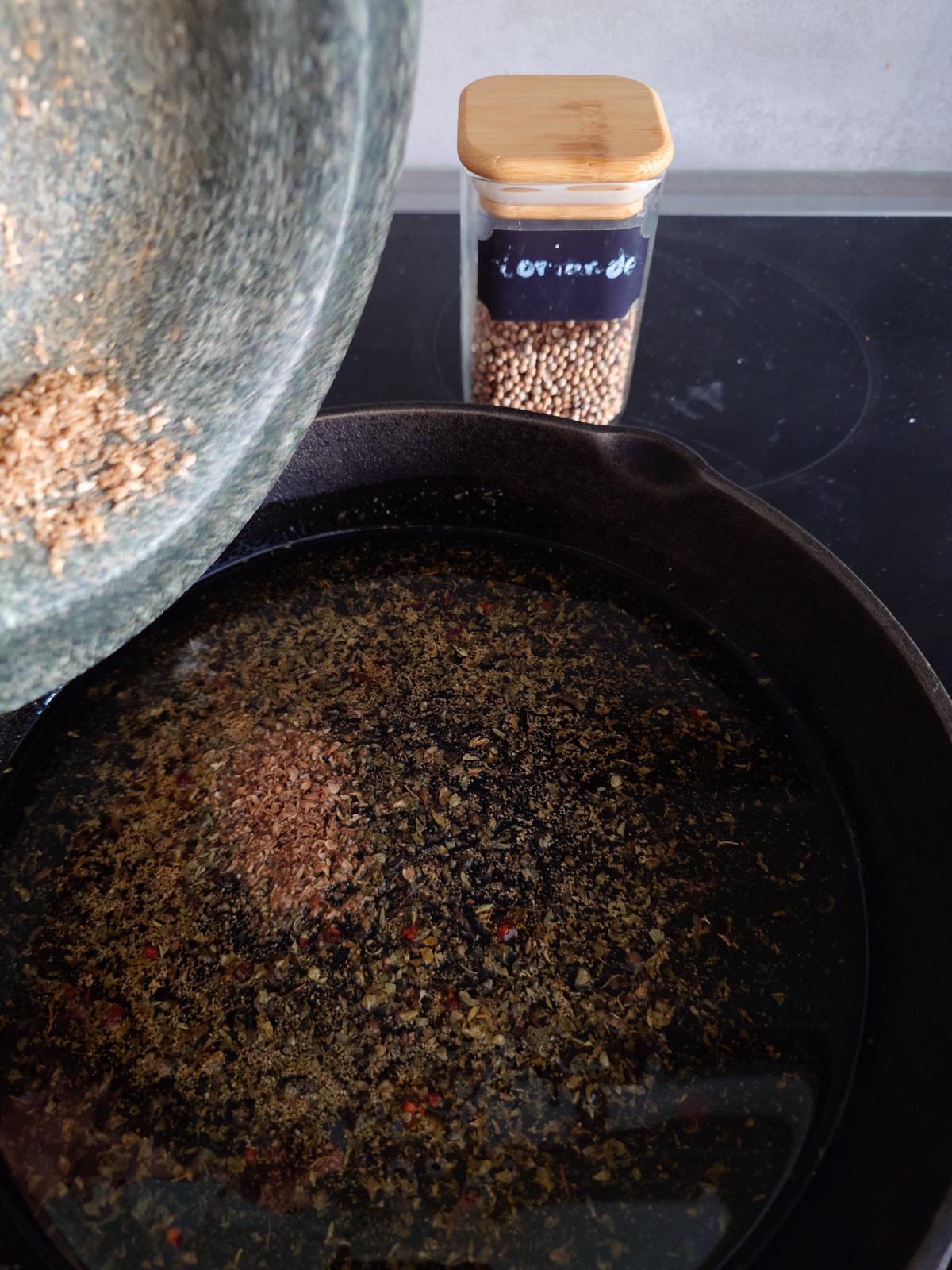 Cracked coriander tipped from the mortar, the jar of whole seed behind