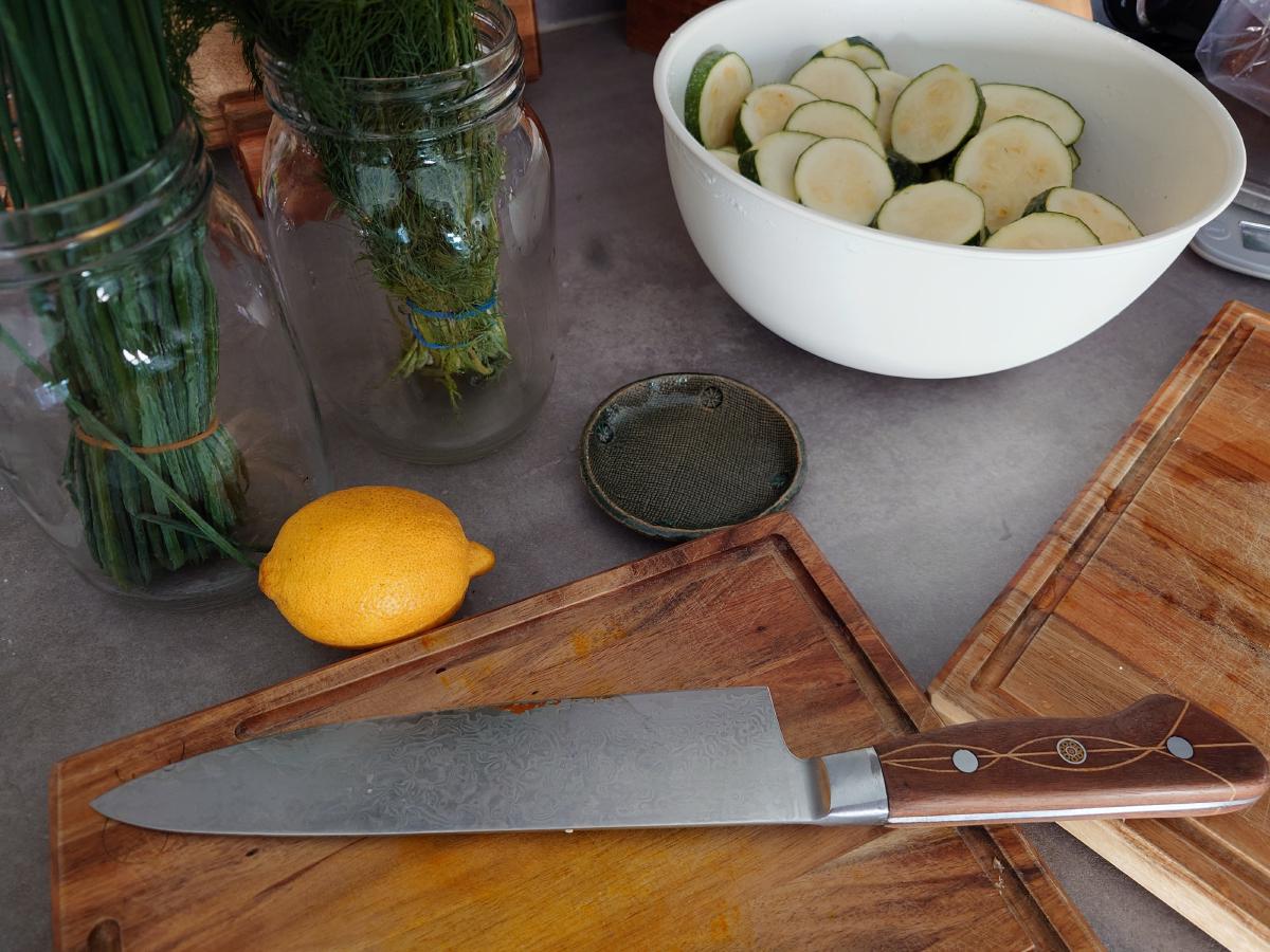 Chives and dill in glass jars of water, a lemon, and the bowl of salted rounds